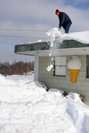 Knocking snow off roof of ice cream shop